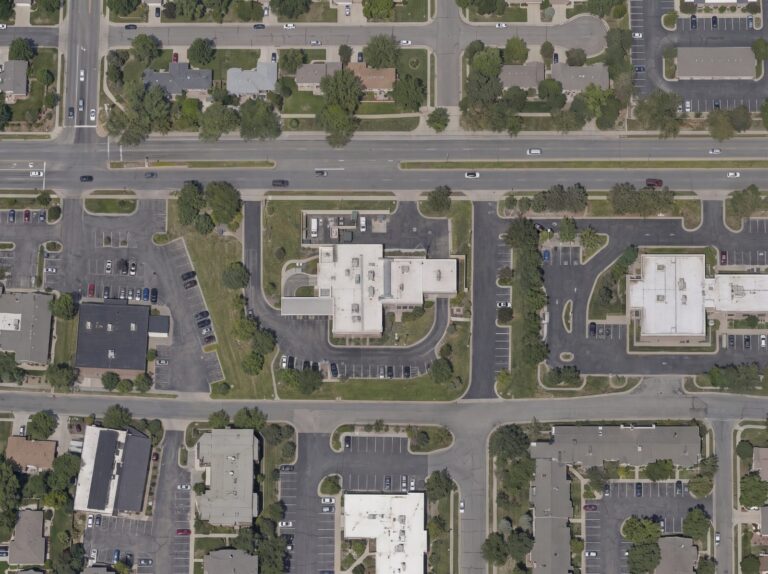 Aerial view of a suburban bank branch with a drive-through lane and secured rear service yard