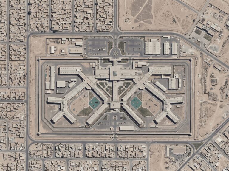 Aerial view of a correctional facility with layered perimeter fencing