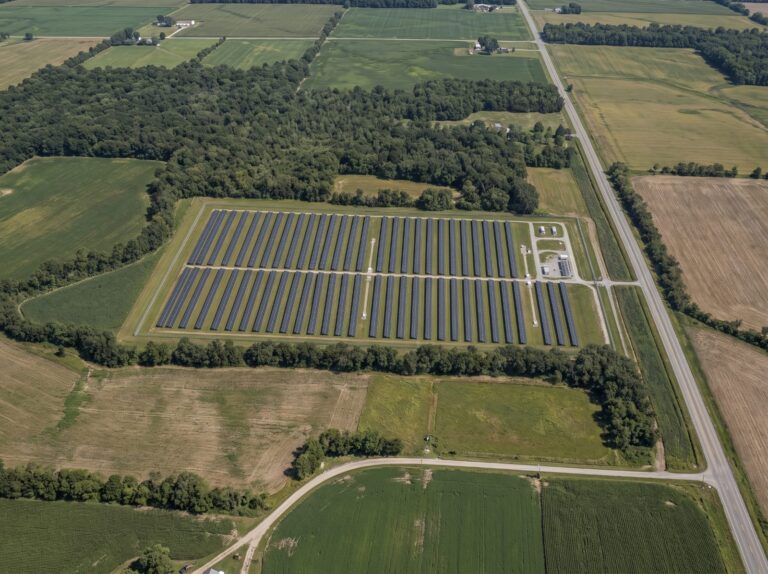Aerial view of a utility-scale solar farm with a fenced perimeter