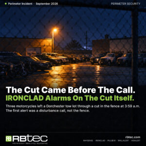 Nighttime view through a chain-link perimeter fence into an urban vehicle tow lot, rows of parked cars, trucks and motorcycles under a single amber floodlight on wet asphalt. Headline reads The Cut Came Before The Call, IRONCLAD Alarms On The Cut Itself.