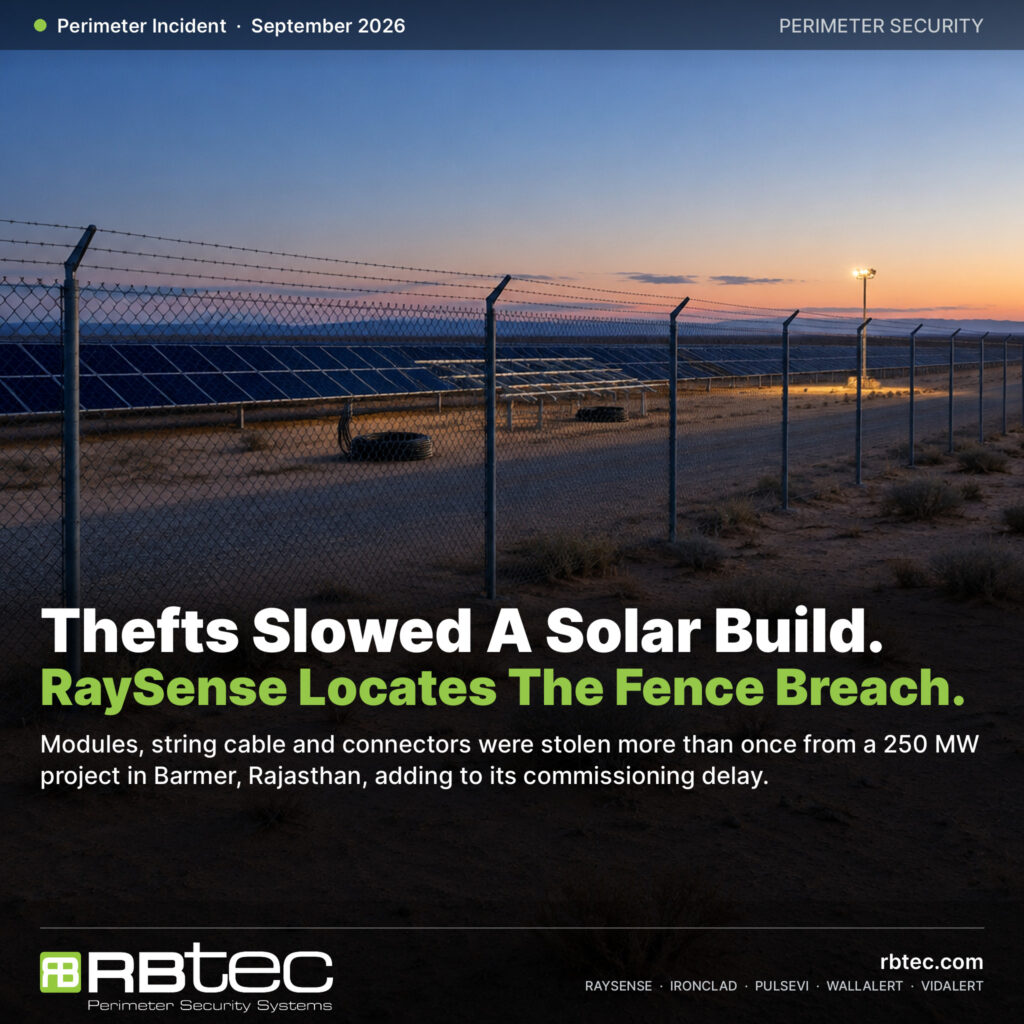 Illustrative image: chain-link and barbed-wire perimeter fence around a desert solar plant at dusk, with empty racking bays and cable coils inside
